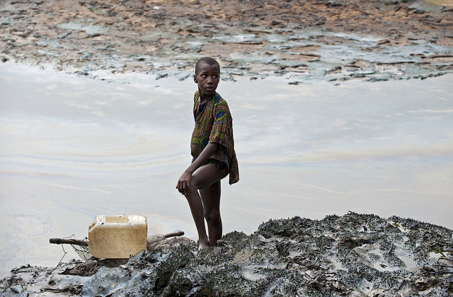 Child-standing-at-oil-polluted-river-banks-in-Goi.jpg